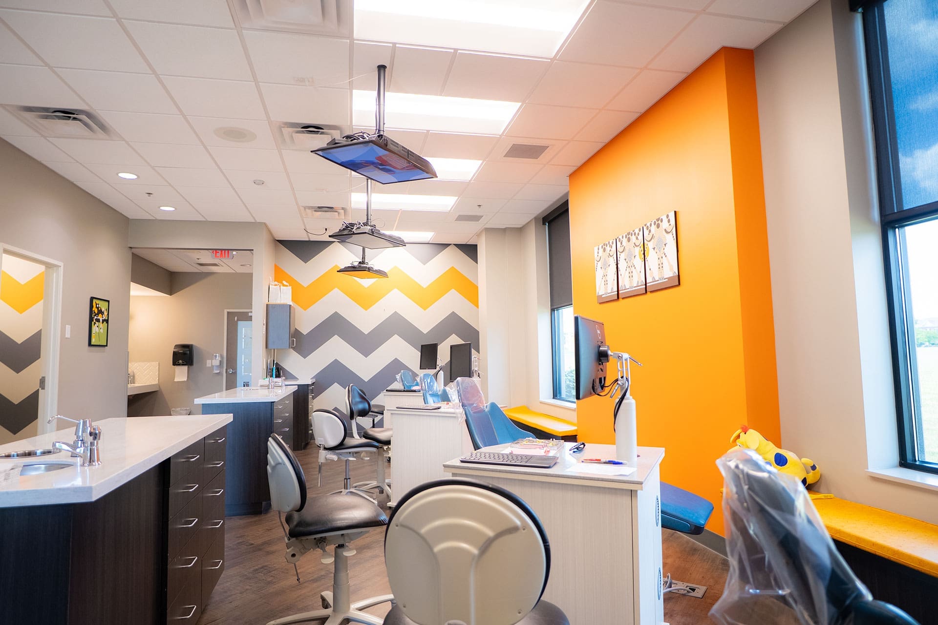 Bright pediatric dental room with colorful chevron walls and treatment chairs at Village Dental at Saxony in Fishers, IN